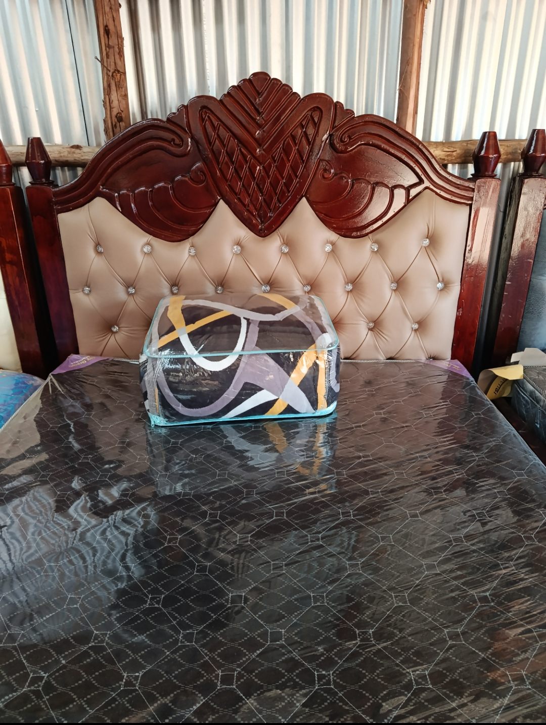 Carved mahogany bed with a beige diamante-buttoned headboard