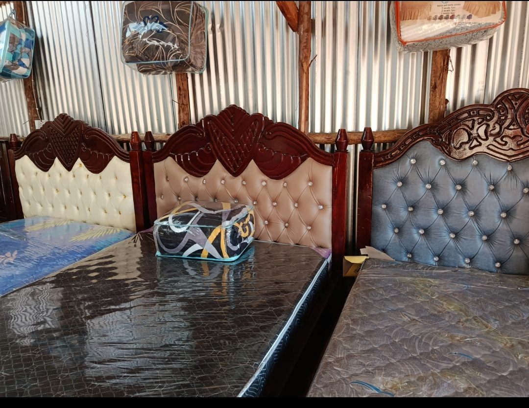A row of finished beds with carved and tufted headboards